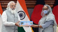 Prime Minister Narendra Modi hands over a representational item to Bangladesh PM Sheikh Hasina as a symbol of India's gift of 1.2 million COVID vaccine doses